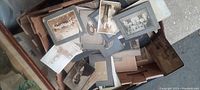 Overview of vintage cabinet card and cardstock photographs scattered in and around a box.