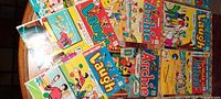 Photo showing a spread of vintage Laugh, Archie, and other old comic books laid out on a round table