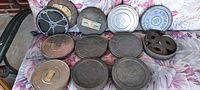 Full layout of eight metal canisters on floral surface, one open showing film reel