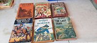 Six antique Zane Grey books with colorful, illustrated dust jackets showing scenes of cowboys, horses, and western landscapes. Books are arranged in two rows on a white surface.