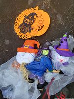 Close-up photo of multiple Halloween hanging decorations including ghost figures with witch hats and an orange owl silhouette decoration