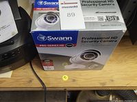 Boxed Swann Pro-Series HD Security Camera 720P model SWPRO-T8350CAM on a wooden surface.