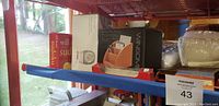 Photo shows wooden desk organizer in packaging, Sudoku books with red and white covers, on a shelf.