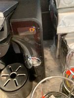 Close-up side view of black Bosch Tassimo coffee machine with cup icon and chrome button