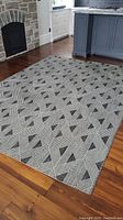 Full view of carpet placed on wooden floor near fireplace and kitchen island, showing complete pattern and layout.