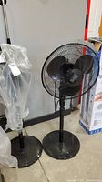 Two Black & Decker floor fans side by side; one fully visible, one wrapped in plastic