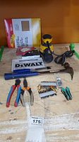 DeWalt orbital sander with hammer, chisel, pliers, driver bits and sandpaper on wooden surface