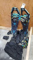 Full view of snowshoes, boots, grips, and black snow guards or pants arranged together.