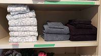 Three stacks of towels arranged on a shelf, showing the different towel colors and styles included in the lot.