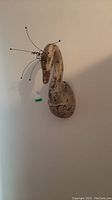 Front view of distressed swan head sculpture mounted on wall, showing full profile and wire crown.