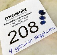 Four faceted sapphire gemstones placed on a white card with seller and auction info, labeled '4 genuine sapphires'