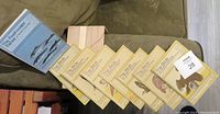 View of ten vintage museum edition books laid out on a surface showing covers featuring birds and fish illustrations, some stacked showing their spines.