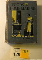 Front cover of the vintage 1939 book 'Foods and Home Making' by Carlotta C. Greer showing illustrated woman cooking and child, with visible wear on spine and edges.