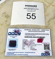 Photo of the gemstone certificate with the genuine ruby and details on weight, cut, origin, and certification.