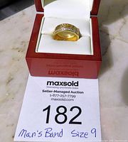 Ring displayed inside a white cushion in a red box with auction label visible.