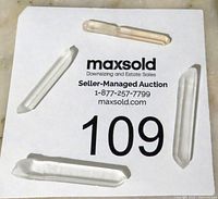 Four quartz crystal points displayed on a white card with auction label 109 on a marble surface, clear and slightly smoky quartz points, varying lengths.