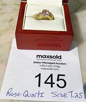 Ring displayed in open red box with white cushion, showing the whole ring and auction lot paper below.
