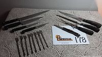 Photo showing all knives and cocktail forks arranged on lace cloth with lot card, including Henckels knives, Universal carving set with stag handles, Cutco paring knife, and cocktail forks.