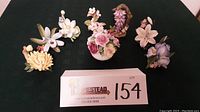 Top view of the full porcelain flower collection and posie pot on black textured surface with lot number card