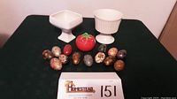 Full lot overview showing two cream-colored vases, red tomato-shaped covered dish, and 13 decorative painted eggs lined in front.