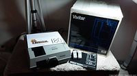 Vivitar 3000AF slide projector with tripod visible behind, original box, instruction manual and two projection lamps on a lace cloth surface.