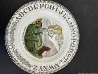 Front view of the ceramic plate with alphabet border and painted illustration of a Native American and buffalo in pioneer scene.