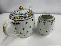 Tea pot and tea caddy side by side showing general shape, decoration, and gold detailing.