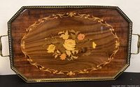 Top view of the wooden tray showing the floral inlay and brass handles on either side.