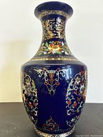 Full front view of the vase showing the floral and geometric cloisonné design on a dark blue background with gold accents.