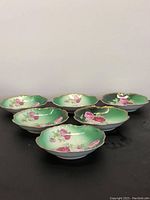 Six porcelain plates with green background and floral patterns, gold plated scalloped edges