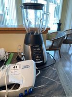 Oster blender with glass pitcher and Black & Decker hand mixer on table.