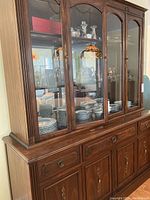 Full front view of Gibbard wooden buffet and glass door hutch displaying shelves with glassware inside.