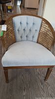 Front view of vintage chair showing caned sides, tufted fabric backrest, and upholstered seat