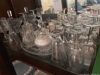 Photo showing assortment of stemmed glasses, cream and sugar set, candy bowl on a tray