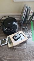 Photo showing black Hyundai CD player, steam iron, white RadioShack device, digital timer, and power cords.