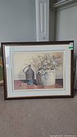 Full view of the framed still life print with dried flowers in ceramic and wicker containers on a wooden surface.