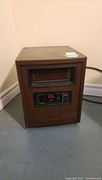Full view of the brown rectangular portable heater showing the general shape, color, and placement of controls and heater element.