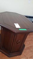 Closed view of the octagonal wooden side table showing dark stained wood with paneled vertical groove design and beveled top edge.