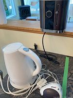 Paderno toaster, white electric kettle, and white electric can opener displayed on kitchen counter, cords visible