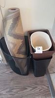 Photo of four plastic waste bins stacked and grouped, with an area rug rolled and inserted in one bin corner