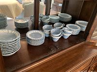 Overall view of Wedgwood dinnerware set arranged in stacks on wooden buffet