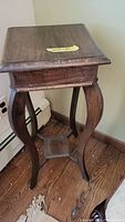 Side view of vintage wooden corner table showing rounded legs and small bottom shelf.