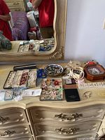 Wide shot of all assorted costume jewelry items arranged on a beige dresser with a mirror.