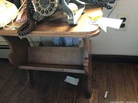 Front angle showing the side panel and lower magazine rack of the solid wood vintage style magazine table with visible signs of wear.