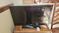 Full front view of the 32-inch Samsung TV with remote control placed on a wooden surface.