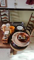 Overview of various servingware and kitchen items displayed on a wooden table, including large floral ceramic bowl, wood bowl with utensils, and coffee grinder.