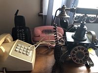 Group photo of five vintage telephones showing variety in styles including rotary and push button.