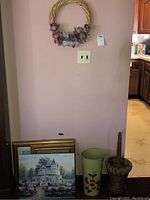 Group of wall art and decor items against a pink wall, showing general arrangement and items included in the lot.