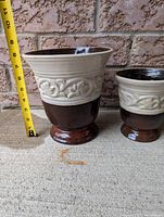 Brown and cream ceramic plant pots showing height with measuring tape, about 9-11 inches tall