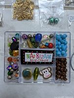 Plastic organizer with various beads in multiple materials, shapes and colors including blue round, brown round, novelty monkey bead, and multicolor patterned beads.